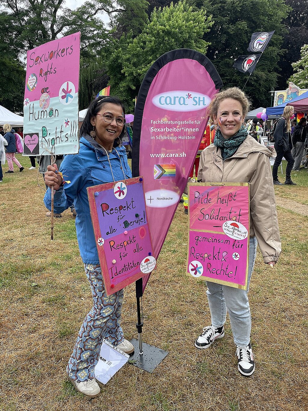 Zwei Frauen an einer Beachflag mit Demo-Transparenten